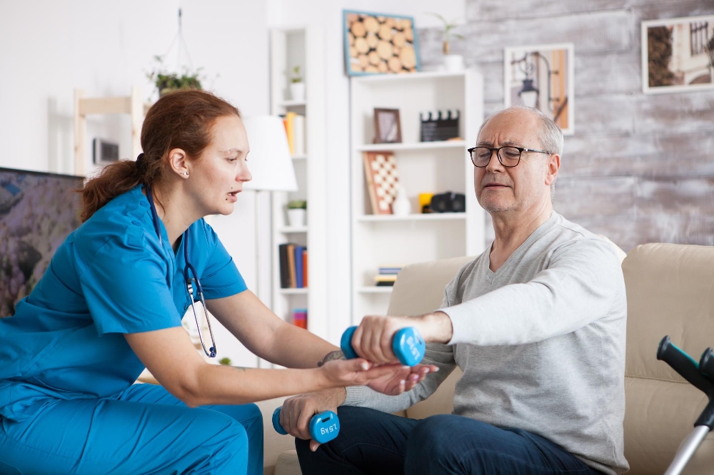 Nurse helping an older man lift a blue dumbbell, similar to occupational therapy for rheumatoid arthritis exercises 